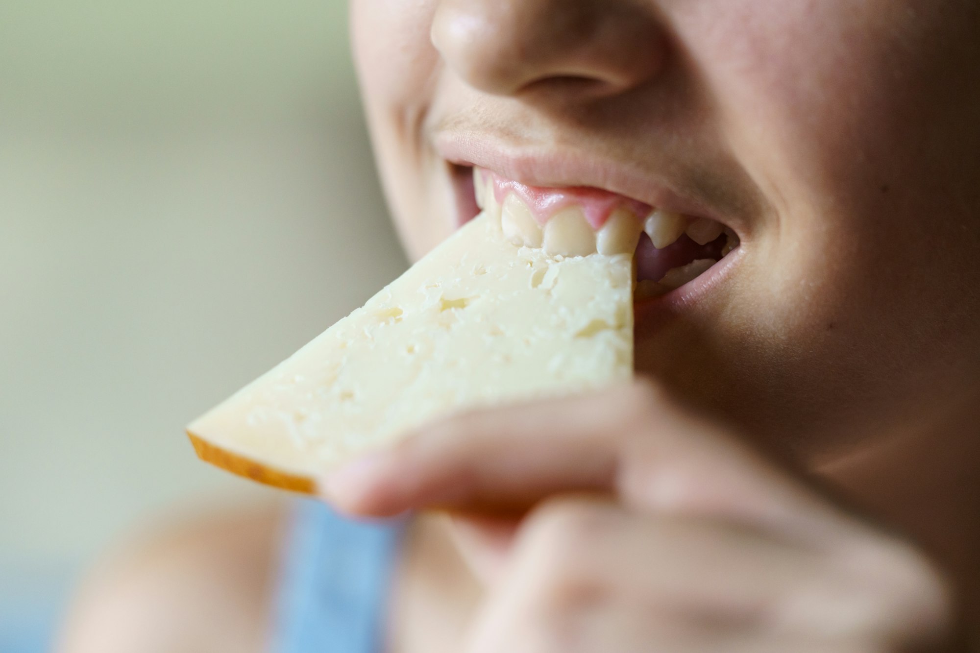 Crop happy unrecognizable girl biting fresh cheese slice