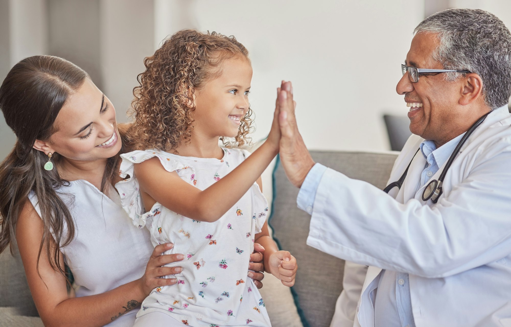 Family, medical and high five with girl and doctor in consulting hospital room for healthcare, trus