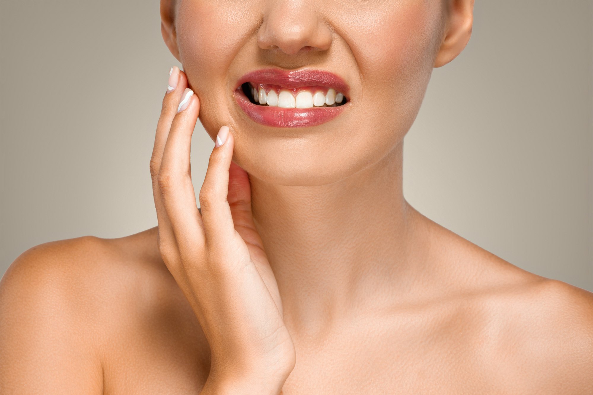 Sad young european lady puts hand to cheek, suffering from toothache, tooth sensitivity